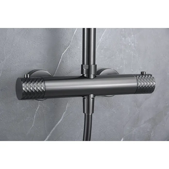 Imex Génova Sistema de ducha - Grifo termostático, Black gun metal - Primer plano de un moderno accesorio de ducha antracita con mangos giratorios texturizados montado en una pared de mármol gris.