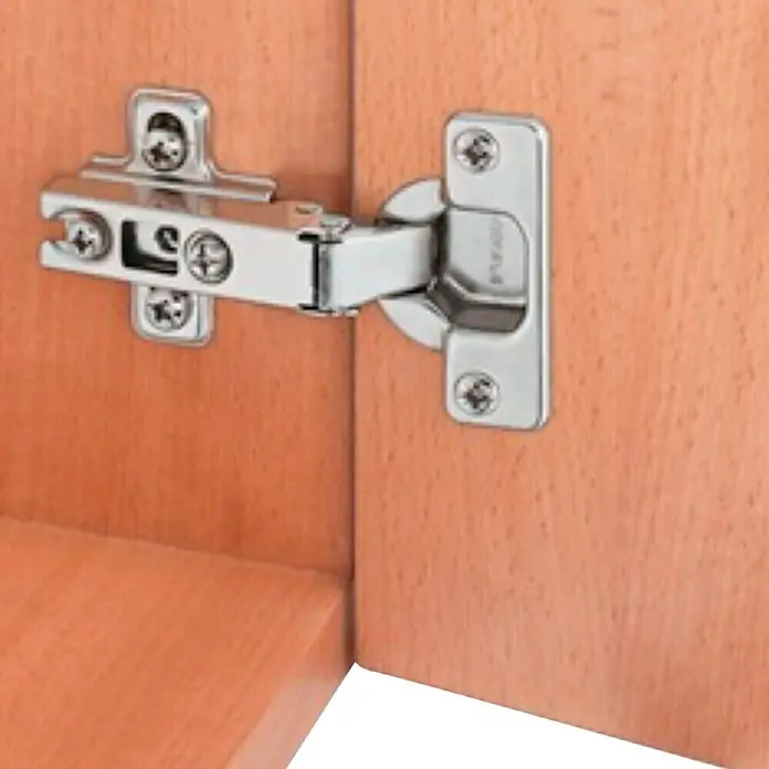 Stabilit Bisagra de cazoleta - Diámetro cazoleta: 35 mm - Imagen de una bisagra de armario fijada a una puerta de madera. Los herrajes son de metal plateado y se fijan con tornillos.