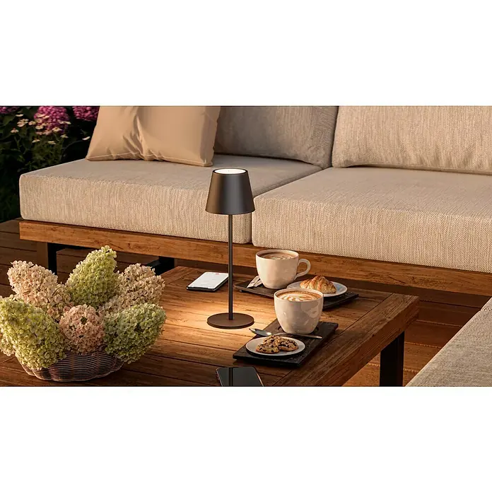 Starlux Paola Akku-Tischleuchte - 3 W, L x B x H: 11 x 11 x 36 cm, Schwarz, Warmweiß - Elegante Tischleuchte auf einem Holztisch mit Kaffee und Gebäck, ideal für gemütliche Stunden im Freien.