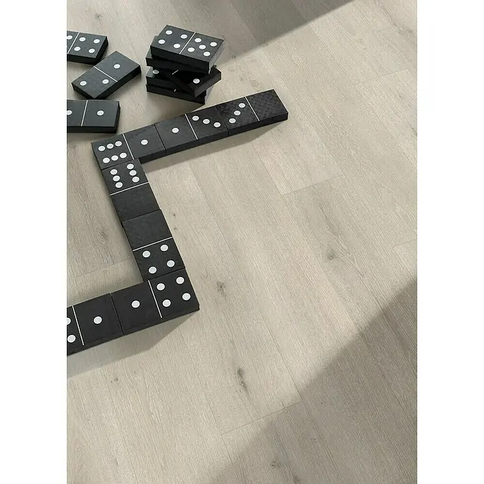 Parador Designbodenmuster Modular ONE Eiche Urban weiß - 200 x 194 x 8 mm, Landhausdiele - Schwarze Dominosteine mit weißen Punkten liegen auf einem hellen Holzboden und bilden ein unregelmäßiges Muster.