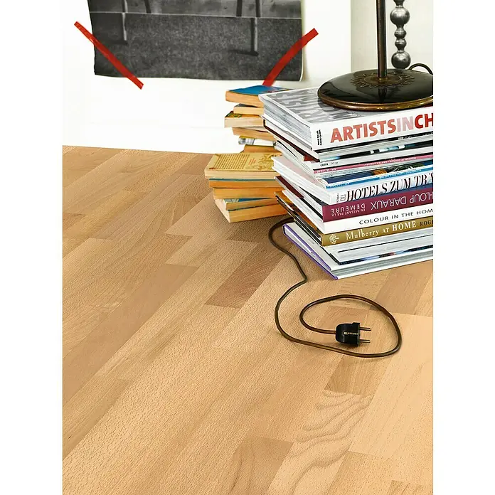 Parador Parkett Basic 11.5 - Buche Natur matt lackiert, Schiffsboden, 2.200 x 185 x 11,5 mm - Stapel Bücher unter einer Lampe mit dem Titel "ARTISTSINCH", die auf einem hellen Holzboden steht.