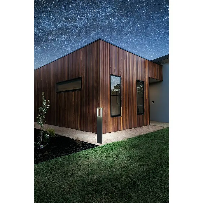 Eglo Riforano Sobremuro exterior - Color del marco: Negro, 6 x 11 x 77 cm, Con bombillas - Elegante luz exterior ilumina un moderno hastial de casa revestido de madera bajo un cielo estrellado, destacando los detalles arquitectónicos.
