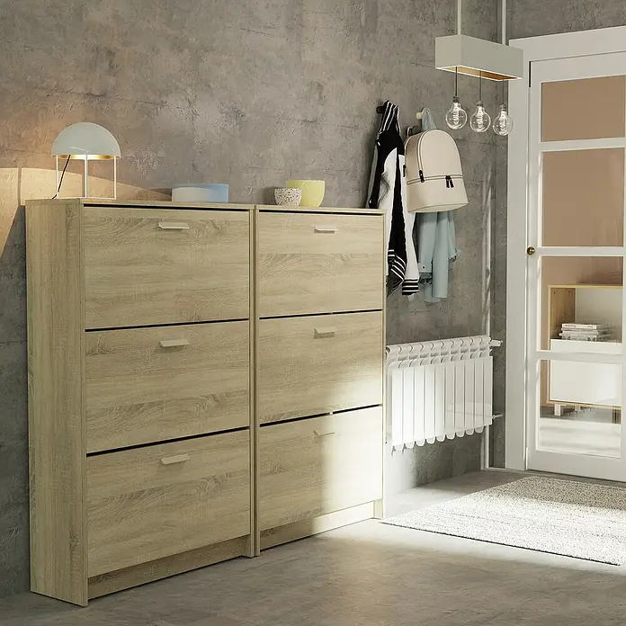 Muebles Pitarch Tibet Zapatero - L x An x Al: 25 x 74 x 119,5 cm, Roble Cambrian, Número de compartimentos: 3 ud. - Dos zapateros de madera clara con lámpara y decoración encima, perchas con chaquetas y una mochila, un radiador y una entrada con alfombra.