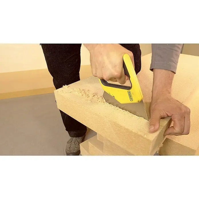 Steico Holzfaserdämmplatte top1.200 x 400 mm, Stärke: 80 mm, Wärmeleitfähigkeit: 0,04 W/(mK) - Ein Mann schneidet ein Stück Dämmmaterial mit einem gelben Stanley-Messer zu, um es passend zu machen. Präzises Arbeiten für die Isolierung.