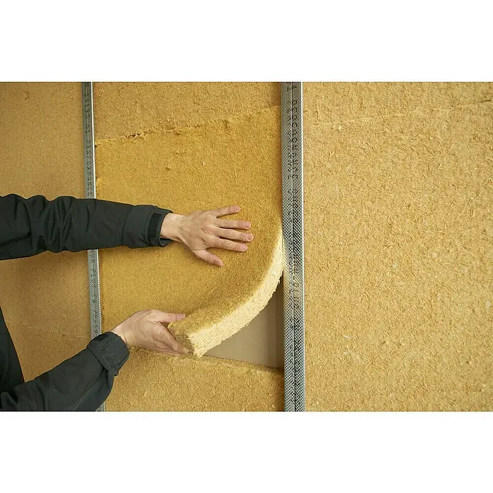Steico Holzfaserdämmplatte flex 0381.200 x 625 mm, Stärke: 60 mm, Wärmeleitfähigkeit: 0,038 W/(mK), 7 Stk. - Ein Arbeiter, der eine goldene Dämmplatte zwischen zwei Metallrahmen an einer Wand anbringt.