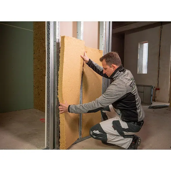 Steico Holzfaserdämmplatte flex 0381.200 x 625 mm, Stärke: 60 mm, Wärmeleitfähigkeit: 0,038 W/(mK), 7 Stk. - Ein Mann bringt Dämmplatten an einer Metallständerwand an, ein wichtiger Schritt für die Wärme- und Schallisolierung im Bauwesen.