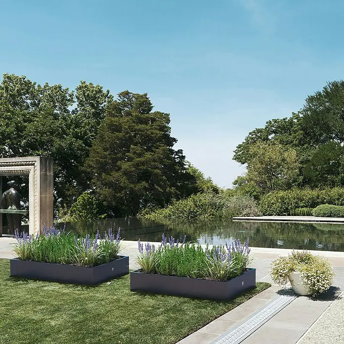 Herstera Garden Pflanzkasten - L x B x H: 150 x 100 x 25 cm - Zwei moderne Pflanzkästen mit Lavendel und Ziergräsern auf einer Terrasse, die einen Garten mit Teich ergänzen.