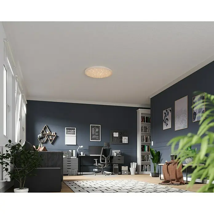 Tween Light LED-Deckenleuchte rund Skyler Star RGBW - 80 W, Ø x H: 74 x 10 cm, Weiß, RGBW - Eine moderne Deckenleuchte mit Sternenmuster erhellt einen stilvollen Arbeitsbereich mit dunklen Wänden und hellen Holzfußboden.
