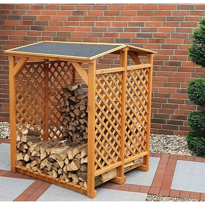 Promadino Kaminholzregal - 120 x 118 x 148 cm, Holz, Braun - Brennholzregal aus Holz mit Dach, gefüllt mit Holzscheiten, vor einer Ziegelmauer und einem Zierstrauch.