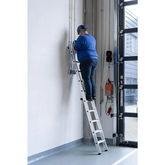 Krause Stabilo Anlegeleiter 10 Stufen - Anzahl Tritte: 10 Stk., Arbeitshöhe: 3,6 m, Belastbarkeit: 225 kg, Aluminium - Mann auf einer KRAUSE Stehleiter bei der Arbeit an Rohren, stabile und sichere Arbeitsumgebung.