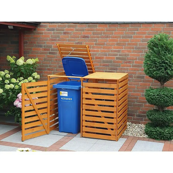 Promadino Mülltonnenbox Variov -  - Das Bild zeigt eine hölzerne Mülltonnenbox mit einer blauen Papiertonne, die den Gartenbereich stilvoll ergänzt und die Mülltrennung erleichtert.