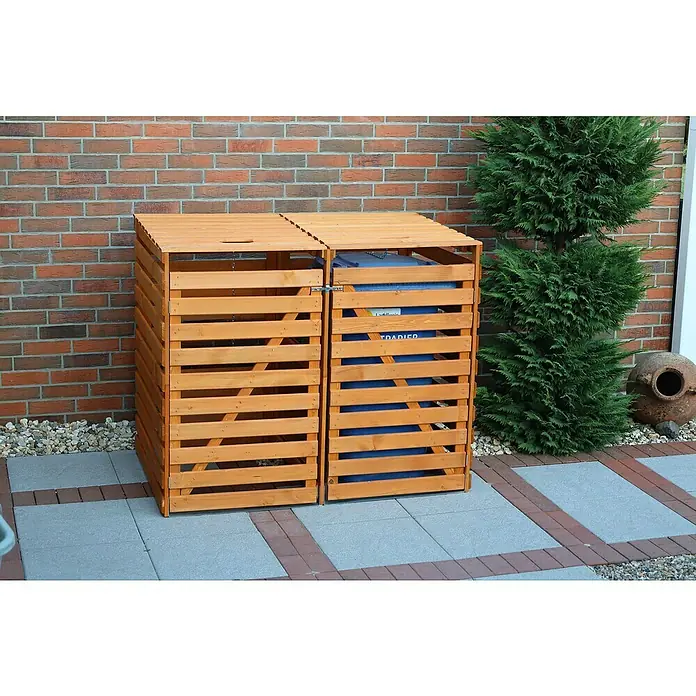 Promadino Mülltonnenbox Variov -  - Zwei hölzerne Mülltonnenboxen stehen vor einer Backsteinmauer und bieten eine stilvolle Lösung zur Aufbewahrung von Mülltonnen im Freien.
