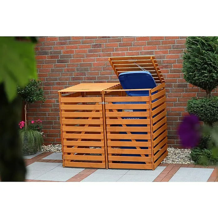 Promadino Mülltonnenbox Variov -  - Eine Doppel-Mülltonnenbox aus Holz mit zwei blauen Mülltonnen steht vor einer roten Ziegelwand und Pflanzen im Garten.