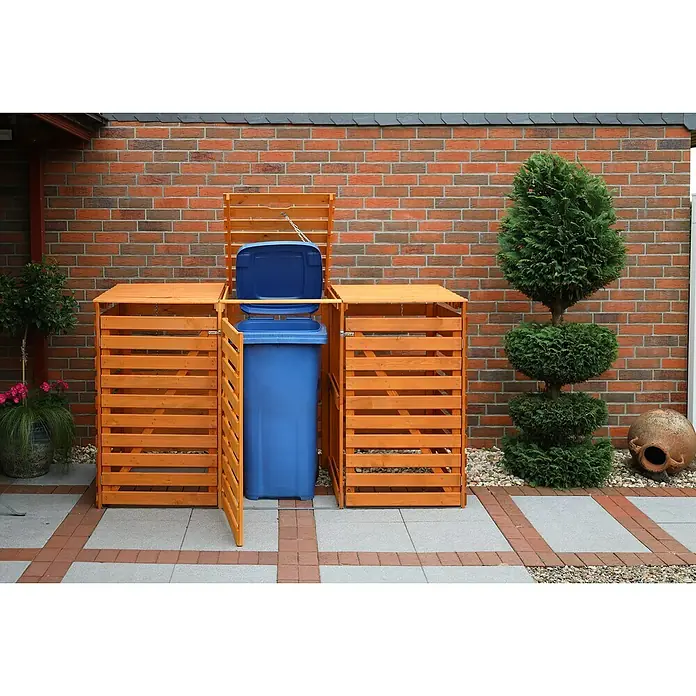 Promadino Mülltonnenbox Variov -  - Foto einer hölzernen Mülltonnenbox im Außenbereich, die eine blaue Mülltonne enthält. Die Box steht auf einem gepflasterten Untergrund.