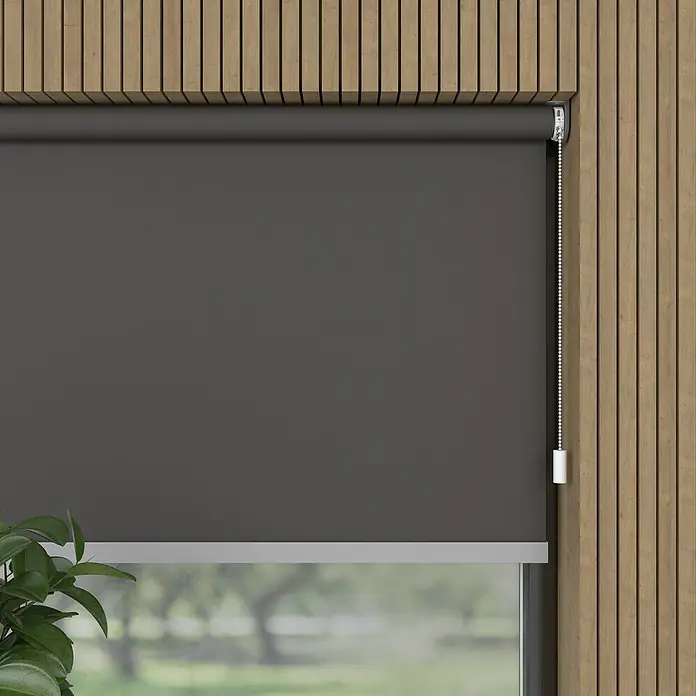 Verdunkelungsrollo Mila Elektrisch - B x H: 60 x 190 cm, Grau, Uni - Eine graue Rollo ist teilweise heruntergelassen und bedeckt ein Fenster, wobei ein Teil der Aussicht noch sichtbar ist. Die Holzverkleidung umrahmt das Fenster.