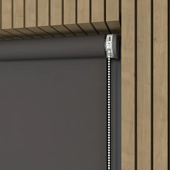 Verdunkelungsrollo Mila Elektrisch - B x H: 60 x 190 cm, Grau, Uni - Nahaufnahme einer grauen Rollgardine mit Kette zur Bedienung, montiert an einer Wand mit Holzverkleidung. Die elegante Rollgardine bietet Sichtschutz.