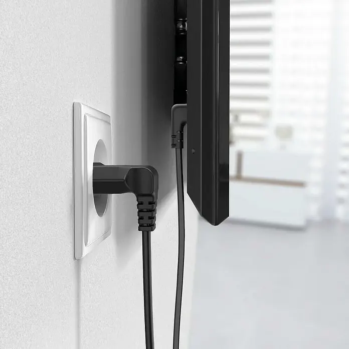 Hama Netzkabel 90° gewinkelt Doppelnut C7 - Weiß/Schwarz, Länge: 1,5 m, Eurostecker, 2,5 A - Nahaufnahme eines rechtwinkligen Netzsteckers, der in eine Steckdose gesteckt ist, ideal für enge Räume hinter Fernsehern.