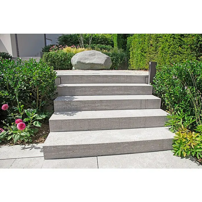 Christoph Blockstufe - Grau, 50 x 32 x 16 cm, Beton - Diese Aufnahme zeigt eine Außentreppe aus Beton, die sich harmonisch in eine grüne Gartenlandschaft mit üppigen Pflanzen einfügt.