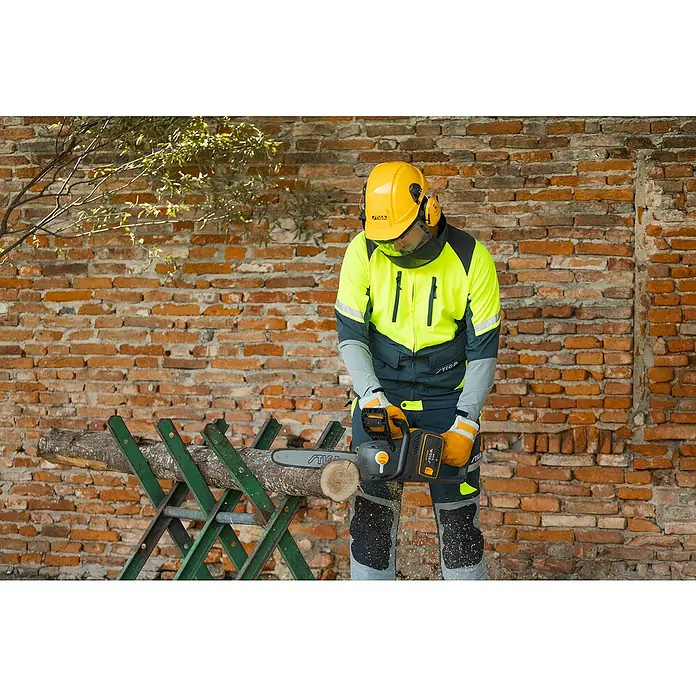 Stiga Akku-Kettensäge CS 700E (14") - 48 V, Ohne Akku, Schwertlänge: 35 cm - Ein Mann mit Schutzkleidung sägt mit einer STIGA Kettensäge Holz vor einer Backsteinmauer.