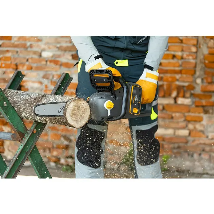 Stiga Akku-Kettensäge CS 700E (14") - 48 V, Ohne Akku, Schwertlänge: 35 cm - Ein Arbeiter mit einer STIGA Kettensäge beim Zersägen eines Baumstamms auf einem Sägebock, umgeben von Holzspänen.