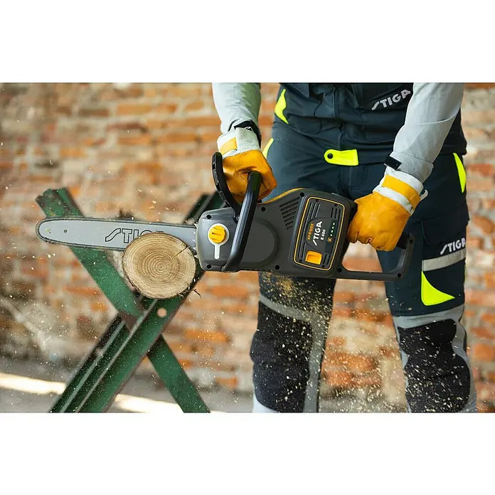 Stiga Akku-Kettensäge CS 700E (14") - 48 V, Ohne Akku, Schwertlänge: 35 cm - Die STIGA E 450 Kettensäge in Aktion beim Sägen eines Holzscheits, getragen von einer Person in Arbeitskleidung und Handschuhen.