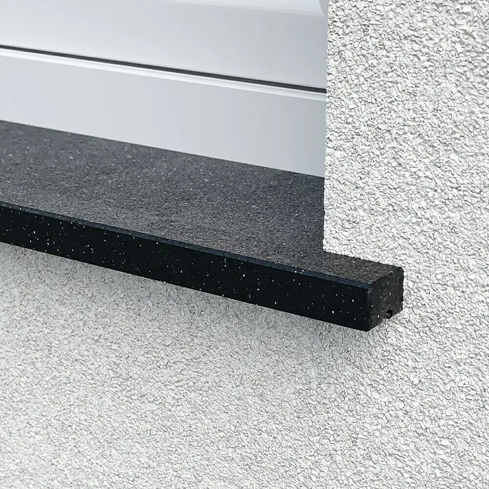 Fensterbank Absolute Black - 240 x 30 x 2 cm, Schwarz, Naturstein - Nahaufnahme einer Fensterbank aus dunklem Granit mit weißen Sprenkeln, eingebettet in eine weiße, strukturierte Wand.