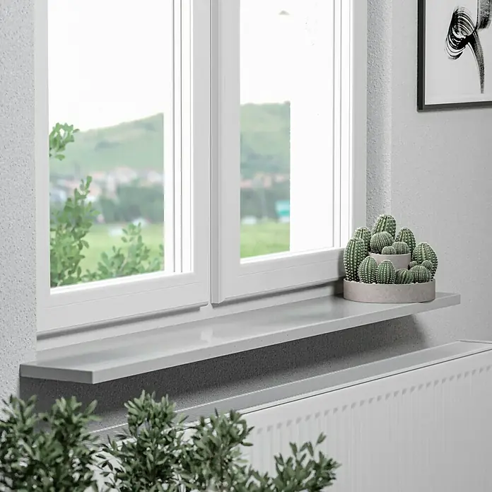 Fensterbank Silver Grey Micro - 240 x 40 x 2 cm, Hellgrau, Kunststein, Agglo-Marmor - Eine graue Fensterbank mit einer Kaktusdekoration darauf, die sich perfekt in ein modernes Interieur einfügt und einen Hauch von Grün hinzufügt.