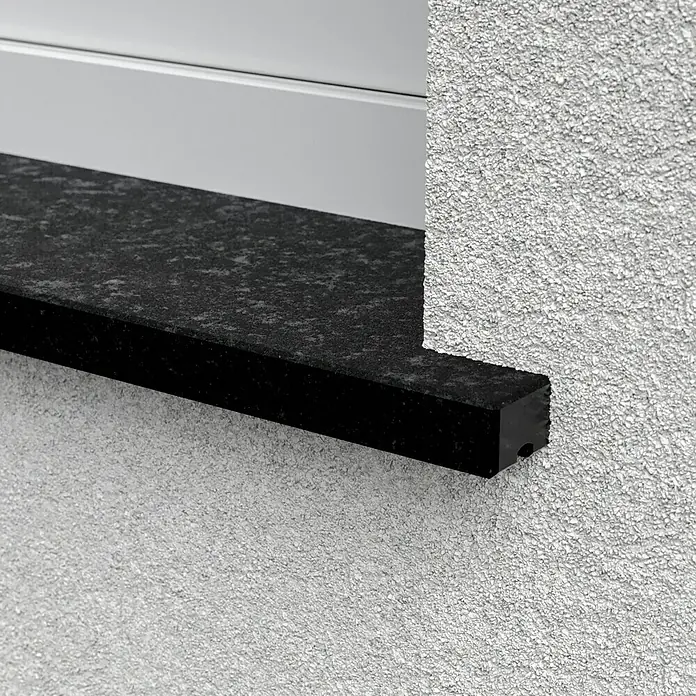 Fensterbank Assoluto Black softgebürstet - 113 x 20 x 2 cm, Schwarz, Naturstein - Detailaufnahme einer Fensterbank aus dunklem Stein an einer Fassade mit grobem Putz. Elegantes Detail für modernes Bauen.
