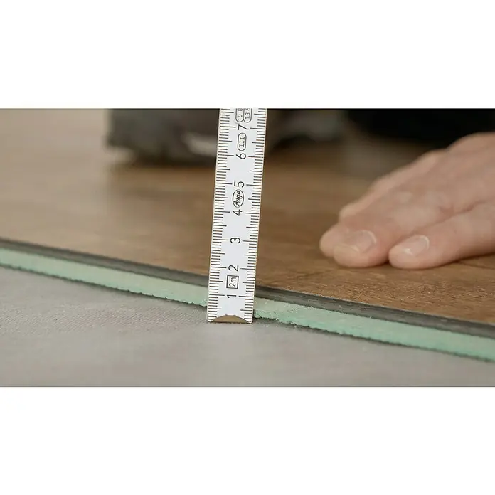 Steico Holzfaserplatte ecosilent790 x 590 mm, Stärke: 3 mm, 20 Stk. - Nahaufnahme einer Vinylbodenplatte mit integrierter Trittschalldämmung, gemessen mit einem Zollstock, der etwa 2 Millimeter Dicke anzeigt.