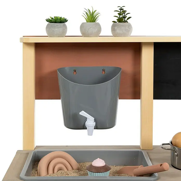 Muddy Buddy Wasserspender Aqua Fun - Grau, L x B x H: 20 x 14 x 18 cm - Bild einer Outdoor-Spielküche mit Wasserhahn, Sandkasten und Dekoration. Ideal für fantasievolles Spielen im Freien.
