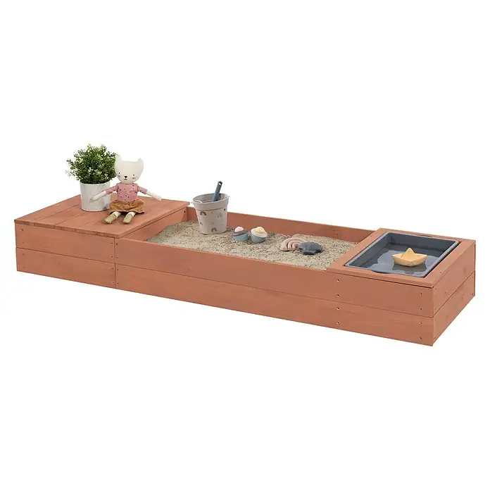 Muddy Buddy Sandkasten Space Saver - 150 x 45 x 20 cm, Holz, Puderrosa - Ein rechteckiger Sandkasten aus Holz mit Spielzeug, darunter ein Stofftier und eine Pflanze.