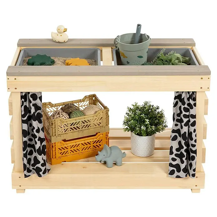 Muddy Buddy Kindertisch zum Matschen Little Leo - L x B x H: 80 x 40 x 55 cm, Holz, Natur/ Grau - Ein hölzerner Spieltisch mit zwei Fächern, gefüllt mit Spielzeug und Pflanzen, sowie Ablageflächen für zusätzliche Gegenstände.