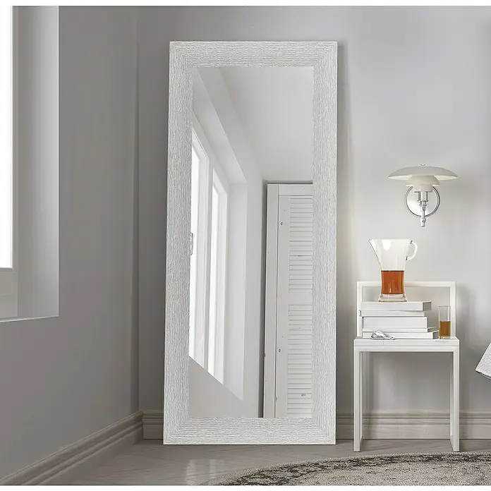 Espejo de pared DM Lisboa - 54 x 144 cm, Plateado - Este artículo muestra un gran espejo blanco de cuerpo entero con un marco texturizado. Se encuentra en una habitación luminosa junto a una mesa pequeña.