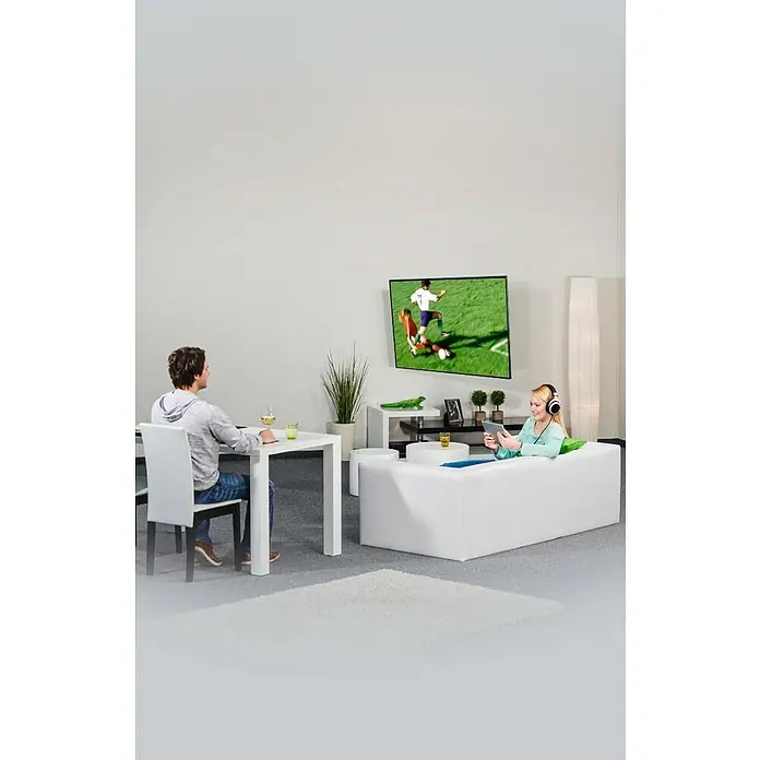Hama TV-Wandhalterung schwenkbar - Passend für: Bildschirmdiagonale 32 - 65″, 81 - 165 cm, Belastbarkeit: 35 kg, Wandabstand: 5,8 cm - 52,1 cm - Ein modernes Wohnzimmer mit weißen Möbeln, einem Fernseher und zwei Personen, die sich entspannen.
