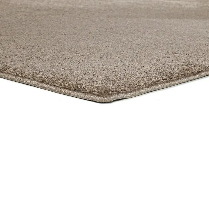 Alfombra de pelo corto Montana - Beige, 120 x 60 cm, 100% Polipropileno - Primer plano de una alfombra beige con un borde limpio, ideal para crear espacios acogedores y resaltar la textura.