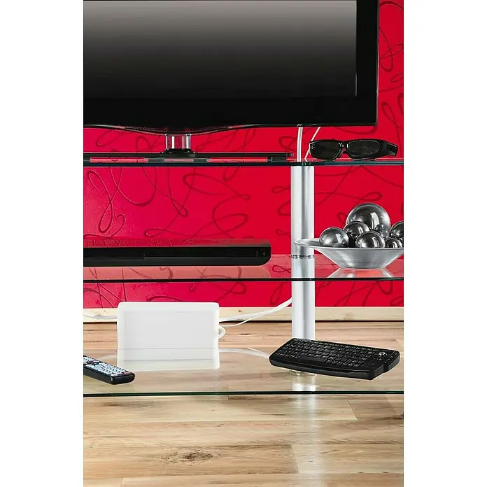 Hama Kabelbox Mini - Weiß - Nahaufnahme eines modernen TV-Ständers aus Glas mit Fernseher, 3D-Brille, Soundbar, Deko-Kugeln, Receiver, Fernbedienung und Mini-Tastatur.