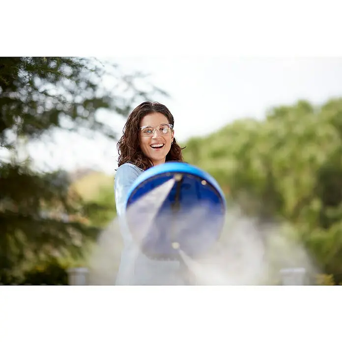 Nilfisk Terrassenreiniger Power Patio - Max. Druck: 200 bar, Passend für: Nilfisk Hochdruckreiniger Compact/Core/Excellent/Premium - Frau mit Schutzbrille hält eine blaue Sprühvorrichtung mit Wassernebel im Freien.