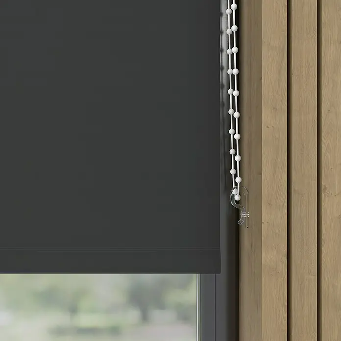 Verdunkelungsrollo Colormatch - B x H: 70 x 190 cm, Anthrazit - Eine Nahaufnahme eines grauen Rollos mit weißer Perlenkette vor einem Fenster und einer Holzwand, die das elegante Design und die Funktionalität hervorhebt.