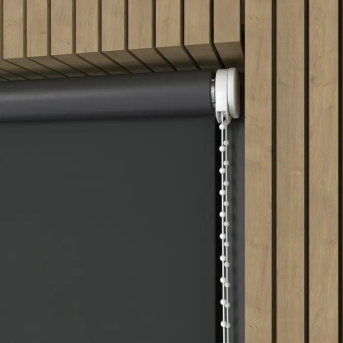 Verdunkelungsrollo Colormatch - B x H: 70 x 190 cm, Anthrazit - Nahaufnahme einer schwarzen Rollo mit weißem Kettenzug vor einer Wand mit Holzpaneelen. Das Rollo ist teilweise heruntergelassen und verdeckt das Fenster.
