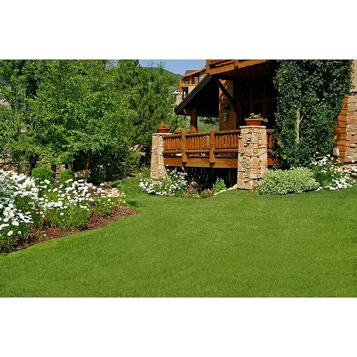 Césped artificial Berna - 4 x 1 m, Altura del pelo: 20 mm, 18.900 puntadas/m² - Un jardín bien cuidado con exuberante vegetación y flores blancas, enmarcando una zona de terraza rústica de madera con pilares de piedra.