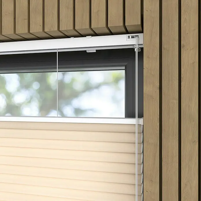 Wabenplissee Tageslicht - B x H: 60 x 175 cm, Taupe - Nahaufnahme einer beigen Plissee-Jalousie vor einem Fenster mit dunklem Rahmen, umgeben von Holzverkleidungen.