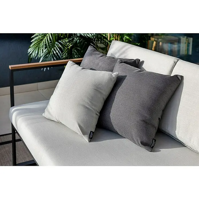 SENSUM Conjunto de muebles Inari - 5 pzs., Aluminio, Negro - Primer plano de cojines decorativos gris claro y gris oscuro en un sofá moderno, con un diseño minimalista y plantas al fondo.