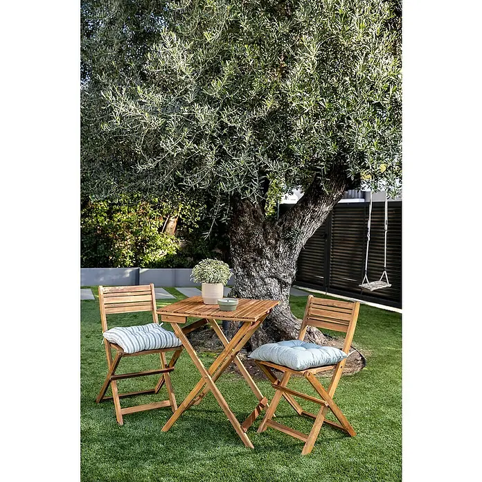 Conjunto de muebles de balcón Bristol - 3 pzs., Madera de acacia, Marrón - Acogedora escena de jardín con una mesa de madera y dos sillas bajo un árbol, ideal para la relajación al aire libre.