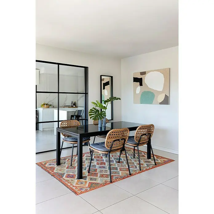 Sunfun Melina Gartenstuhl - Polyethylen, Polypropylen, Stapelbar, Braun, B x T x H: 54 x 59 x 82 cm - Elegantes Esszimmer mit einem schwarzen Esstisch, stilvollen Rattan-Stühlen und einem farbenfrohen Teppich. Die moderne Einrichtung wird durch Kunst und Pflanzen ergänzt.