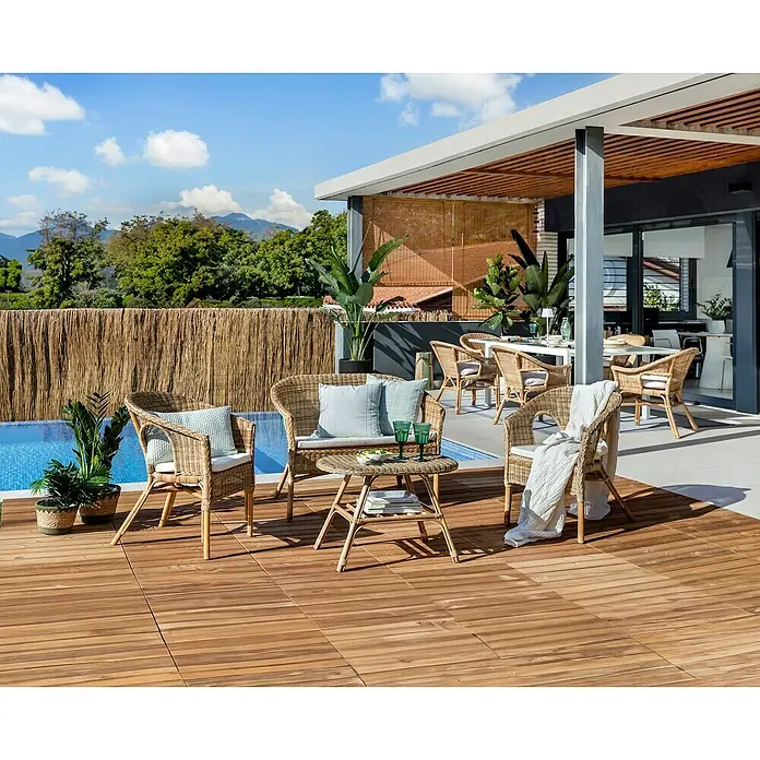 Conjunto de muebles Paula - 4 pzs., Ratán natural, Natural - Escena al aire libre con muebles de ratán, incluidas sillas y una mesa, creando un ambiente relajante en una terraza de madera.