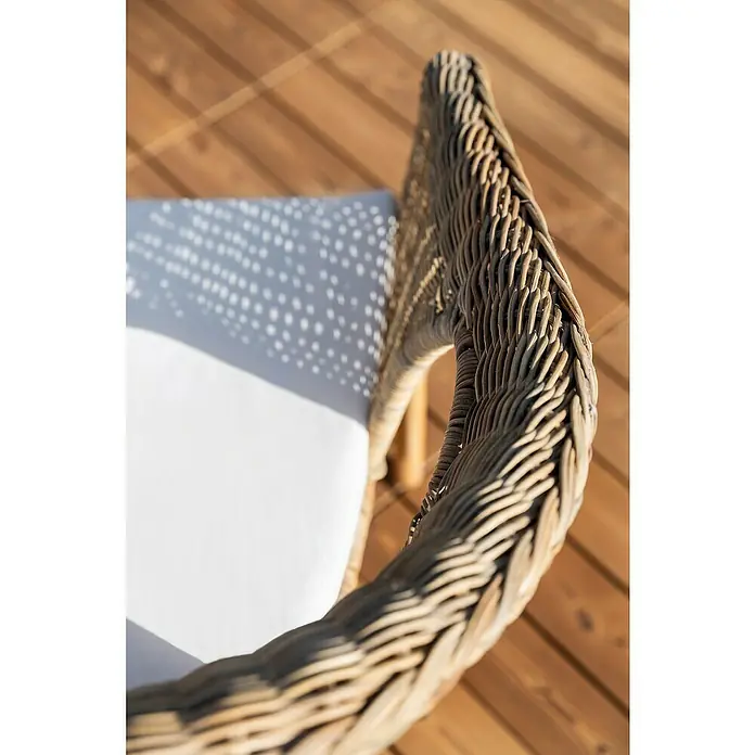 Conjunto de muebles Paula - 4 pzs., Ratán natural, Natural - Primer plano de una silla de ratán con cojín blanco sobre una terraza de madera, destacando la fina artesanía y la textura del material.