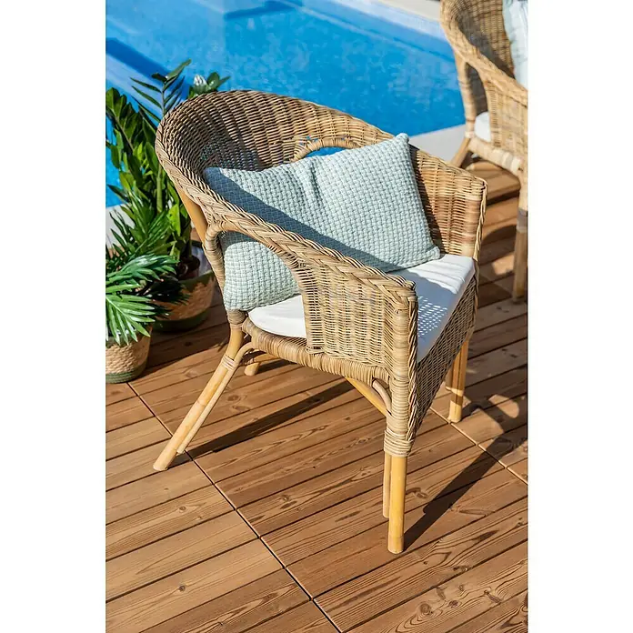 Conjunto de muebles Paula - 4 pzs., Ratán natural, Natural - Primer plano de una silla de mimbre con cojín en una terraza de madera. Ideal para relajarse al aire libre en la piscina.