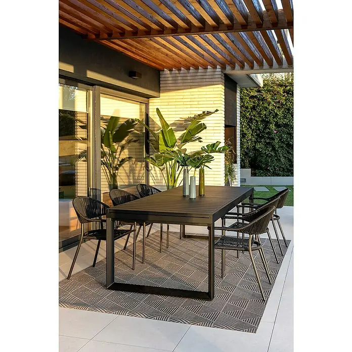 Silla de jardín Melk - 56 x 57 x 80 cm, Antracita, Cuerda, Apilable - Un elegante juego de comedor para exteriores con una mesa oscura y sillas a juego, complementado con jarrones decorativos y una alfombra estampada.