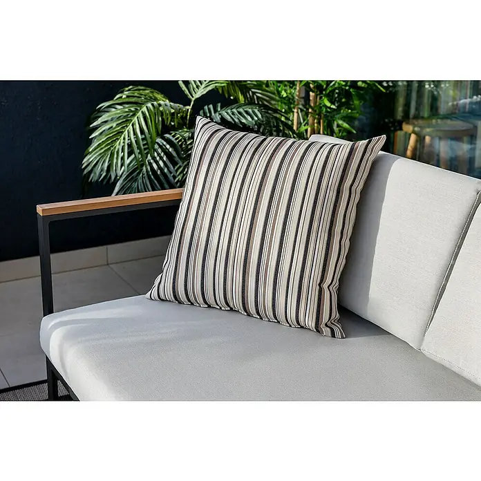 SENSUM Conjunto de muebles Inari - 5 pzs., Aluminio, Negro - Imagen de un cojín decorativo a rayas sobre un sofá claro con un brazo negro y plantas verdes al fondo.