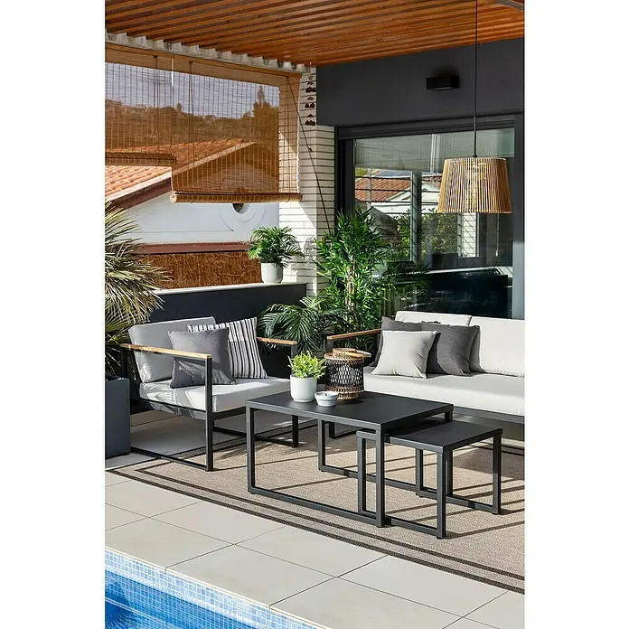 SENSUM Conjunto de muebles Inari - 5 pzs., Aluminio, Negro - Conjunto de muebles de patio con sillas grises, un sofá y una mesa de centro sobre una alfombra junto a una piscina, para una zona de estar exterior elegante.